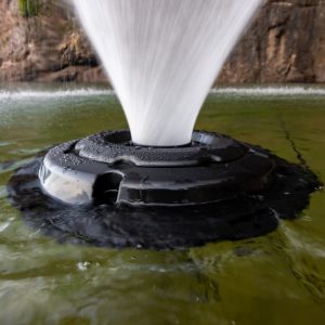 Fountain spout in a body of water with a rocky background